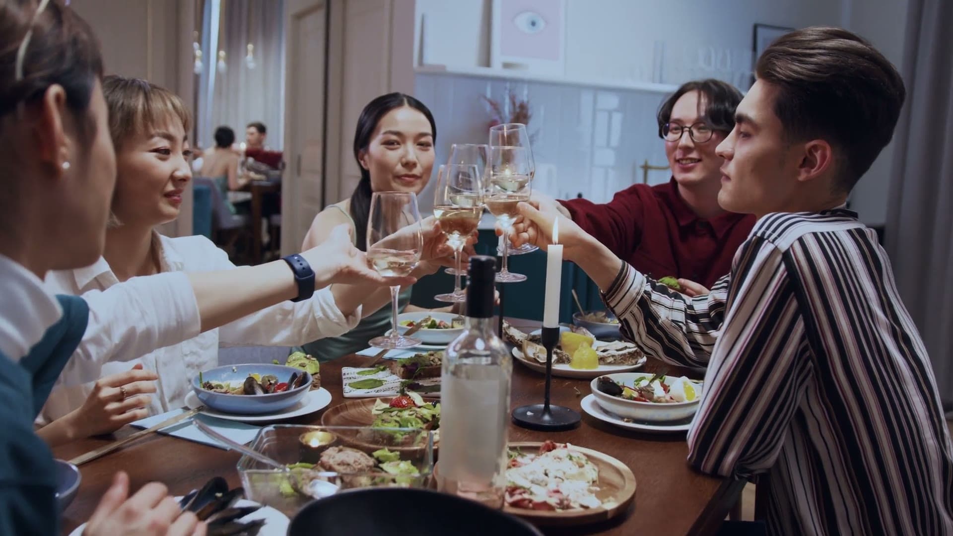 Friends mid-toast at a candlelit dinner